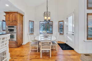 Dining area with a chandelier, light wood-style flooring, a towering ceiling, and recessed lighting