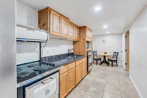 Kitchen featuring light brown cabinets, light tile patterned flooring, dark stone counters, recessed lighting, and extractor fan
