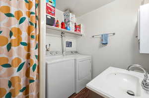 Bathroom with curtained shower, washing machine and dryer, vanity, and dark wood-type flooring
