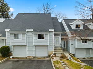 View of front of home with asphalt driveway, roof with shingles, and an attached garage