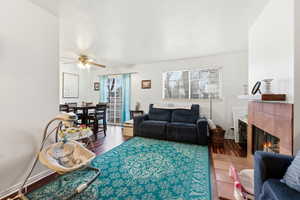 Living area with wood finished floors, a fireplace, and a ceiling fan