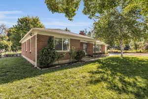View of front facade featuring brick siding, a front lawn, and a chimney