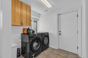 Laundry room featuring washer and clothes dryer, light tile patterned flooring, and cabinet space