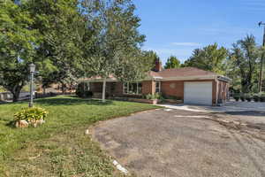 Ranch-style home featuring a front lawn, concrete driveway, brick siding, and a garage