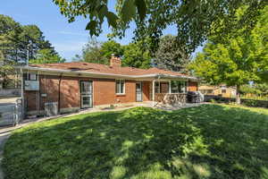 Back of house with brick siding, a patio, and a chimney