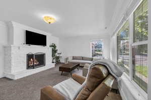 Living room featuring crown molding, a lit fireplace, and carpet flooring