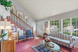 Carpeted living area featuring stairs and high vaulted ceiling