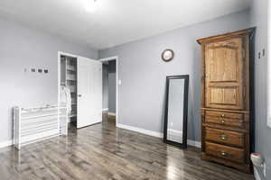 Bedroom with a closet, dark wood-type flooring, and a textured ceiling