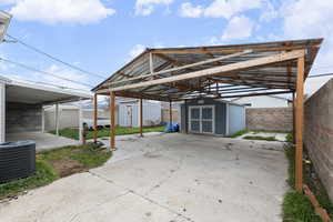 View of car parking with a shed, a fenced backyard, and a detached carport