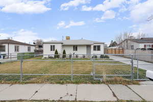 Bungalow-style home featuring a chimney and a fenced front yard