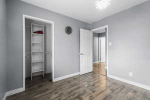 Unfurnished bedroom with dark wood-style flooring and a spacious closet