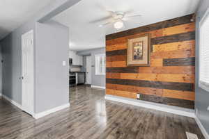 Unfurnished dining area with wood walls, a ceiling fan, dark wood finished floors, and a textured ceiling