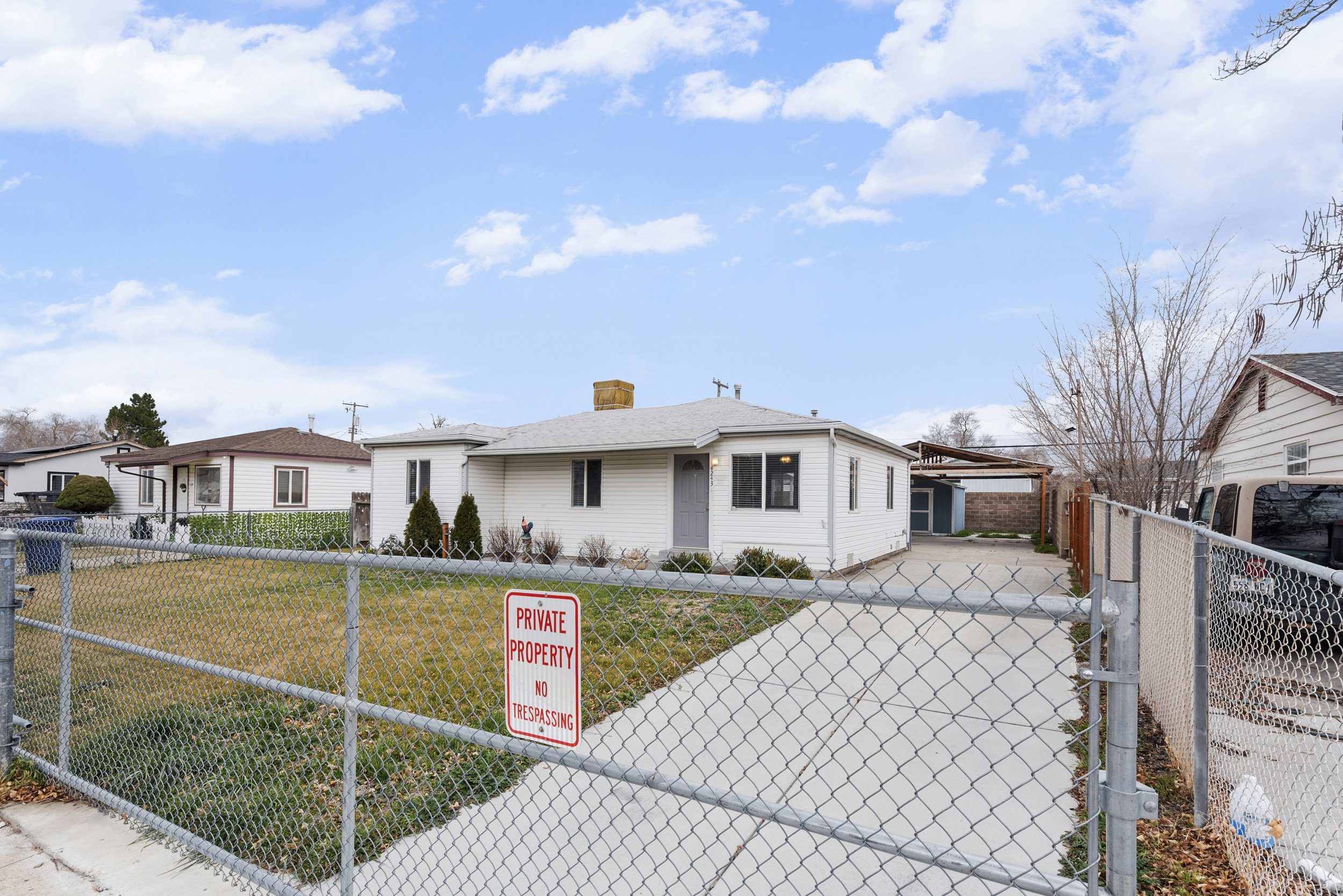 View of front of property featuring a fenced front yard, concrete driveway, a chimney, a gate, and a patio area