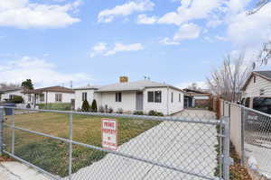 View of front of property featuring a fenced front yard, concrete driveway, a chimney, a gate, and a patio area