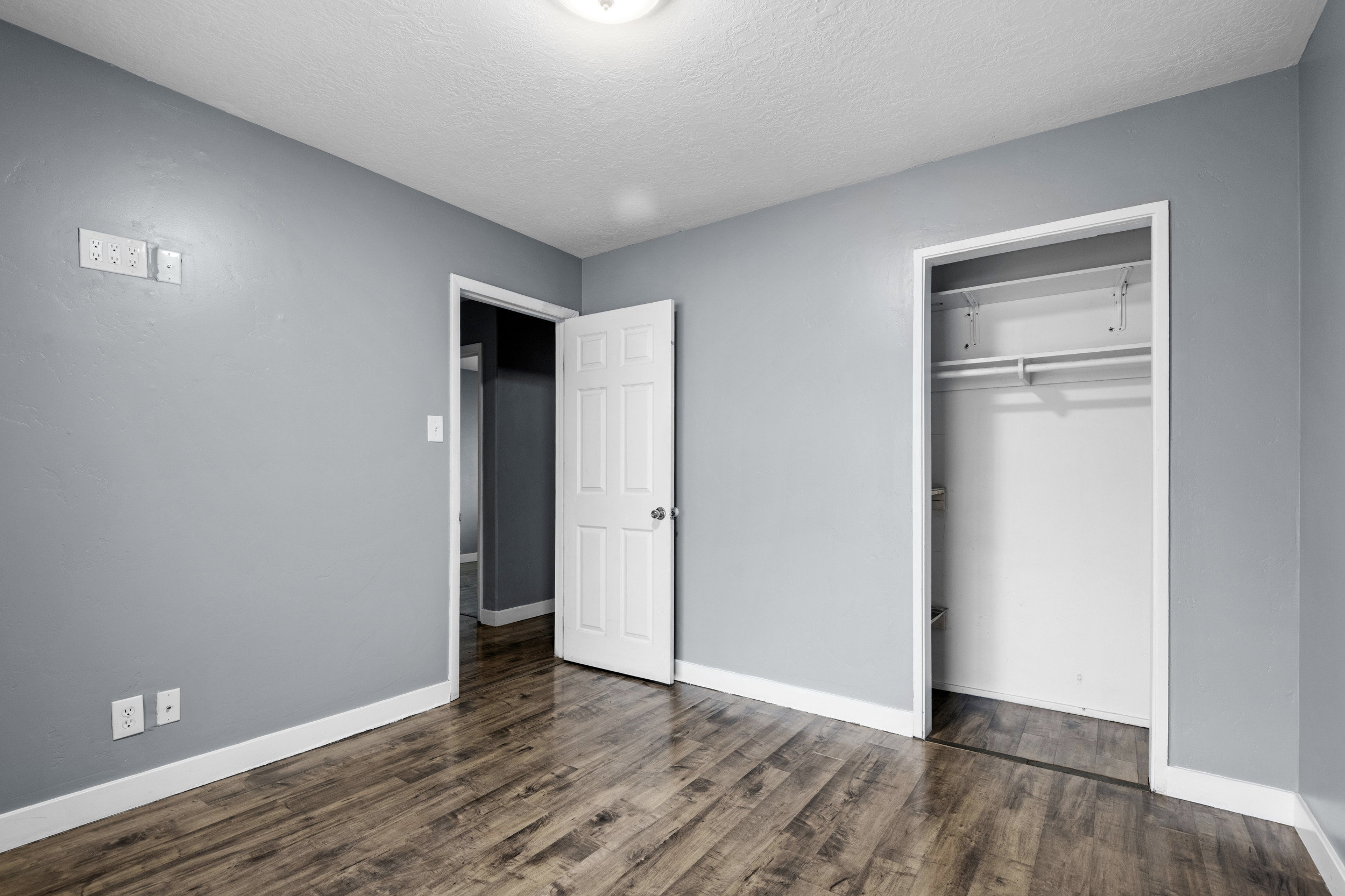 Unfurnished bedroom with a textured ceiling, a closet, and dark wood-style floors