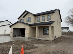 View of front facade featuring stone siding, board and batten siding, driveway, and a porch