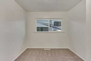 Empty room with light colored carpet and baseboards