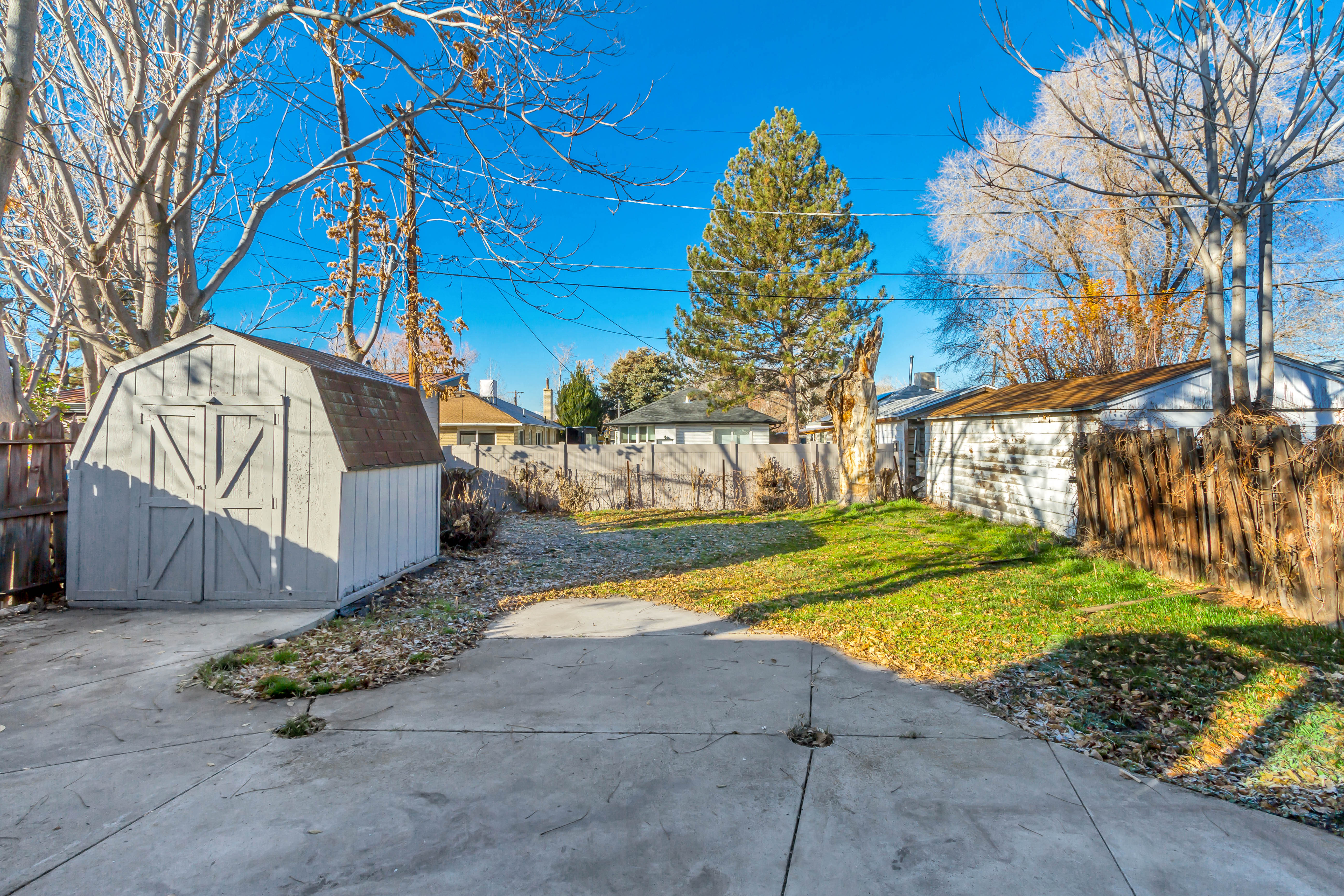 Fenced backyard featuring a storage unit