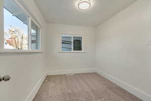 Spare room featuring light colored carpet and baseboards