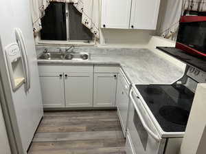 Kitchen with white appliances, light countertops, light wood-type flooring, and white cabinets