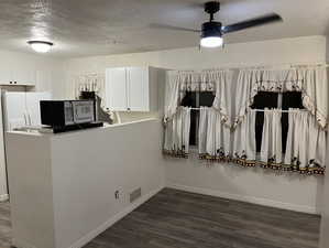 Kitchen featuring a textured ceiling, dark wood-type flooring, white cabinets, a ceiling fan, and white refrigerator with ice dispenser