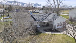 Back of house with a mountain view, a yard, roof with shingles, and a residential view