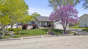 View of front facade with brick siding, a front lawn, covered porch, concrete driveway, and a garage