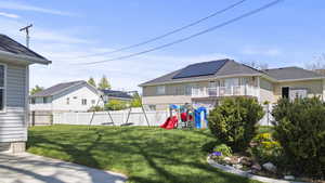 Fenced backyard with a playground and a balcony
