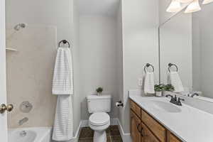 Full bathroom featuring vanity, bathtub / shower combination, and dark tile patterned floors