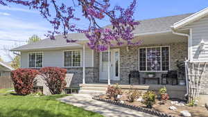 View of front of home with roof with shingles, brick siding, and a porch