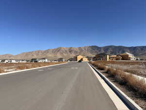 View of asphalt road featuring a mountain view, curbs, and a residential view