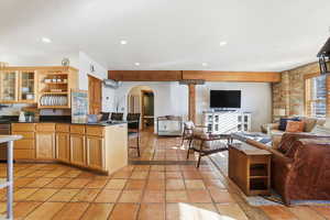 Kitchen featuring open shelves, a kitchen bar, open floor plan, glass insert cabinets, and arched walkways