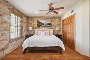 Bedroom featuring brick wall, hardwood / wood-style flooring, ceiling fan, a closet, and recessed lighting