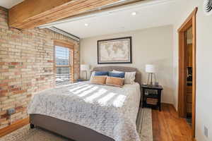 Bedroom with brick wall, wood-type flooring, and recessed lighting
