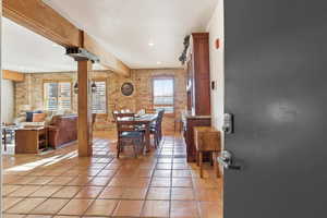 Dining space with brick wall, recessed lighting, beam ceiling, and light tile patterned flooring