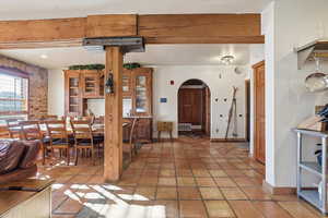 Dining room with arched walkways, beamed ceiling, and light tile patterned flooring