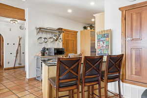 Kitchen with a breakfast bar, arched walkways, black microwave, dark countertops, and recessed lighting
