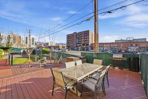 Wooden deck with a city view, grilling area, and outdoor dining area