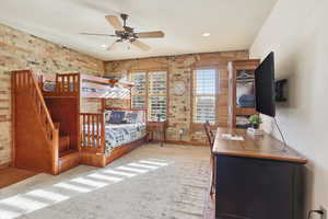 Carpeted bedroom featuring brick wall, ceiling fan, and recessed lighting