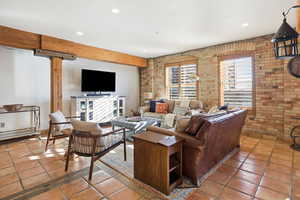 Living room featuring brick wall, recessed lighting, and tile patterned floors