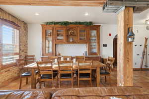Dining area with light tile patterned floors, arched walkways, brick wall, and recessed lighting