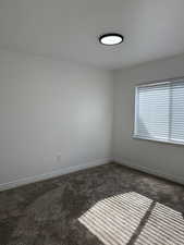 Spare room with dark colored carpet and a textured ceiling