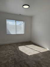 Carpeted empty room with a textured ceiling and baseboards