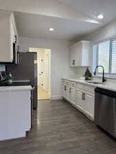 Kitchen featuring white cabinetry, appliances with stainless steel finishes, dark wood-style flooring, recessed lighting, and light stone counters