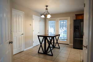 Unfurnished dining area featuring a chandelier and light tile patterned floors