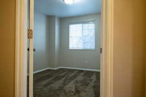 Empty room featuring dark colored carpet