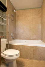 Full bathroom with tile patterned flooring, tiled shower / bath, a textured ceiling, and tile walls