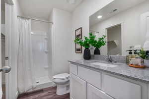 Full bath featuring vanity, a shower stall, and dark wood-style floors