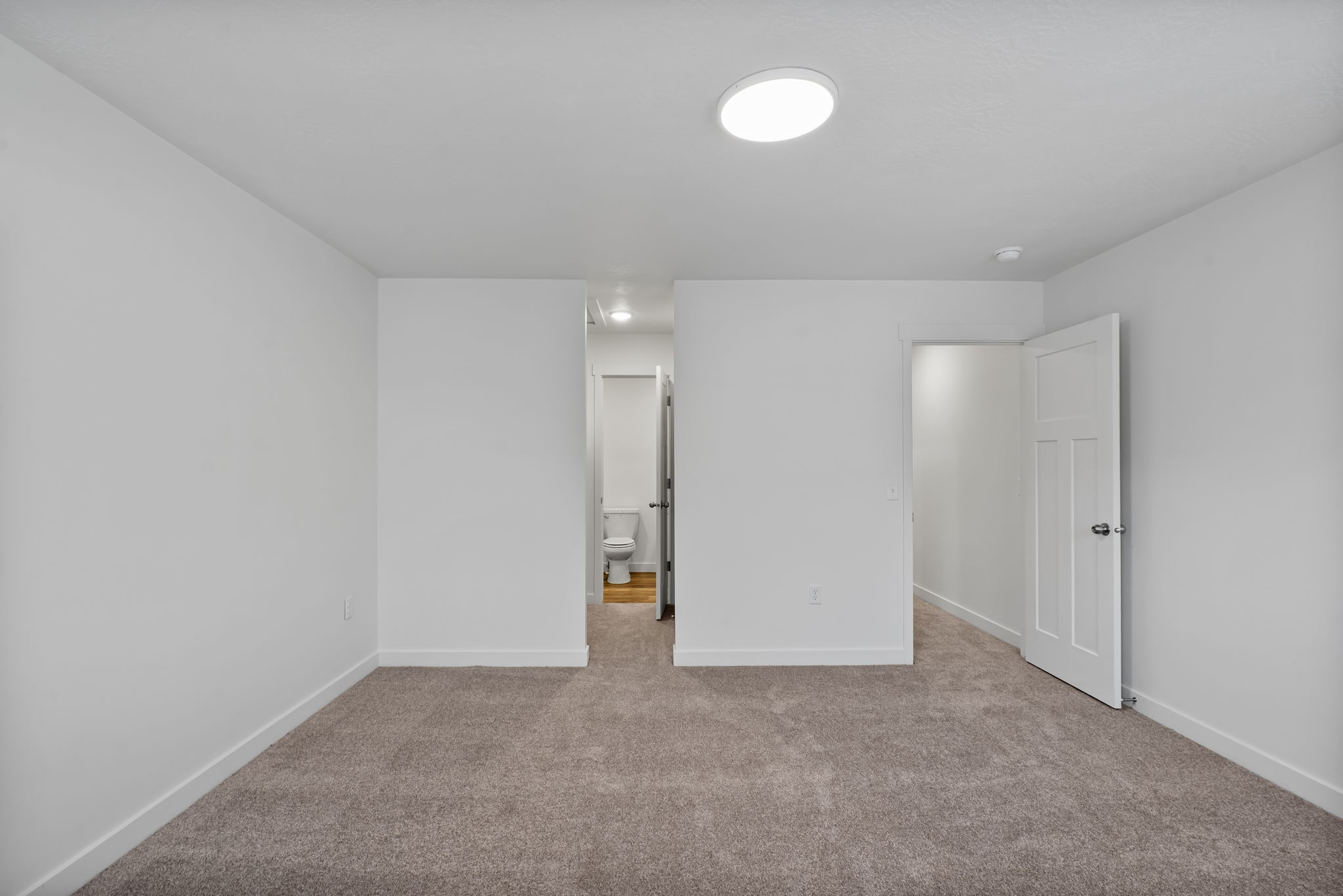Unfurnished bedroom featuring light colored carpet and connected bathroom