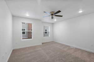 Primary bedroom with light carpet, healthy amount of natural light, and ceiling fan